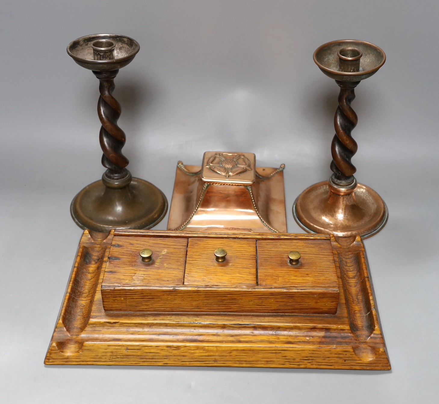 A copper Arts & Crafts inkwell, a pair of A Jones turned candlesticks and an early 20th century oak ink stand (4)